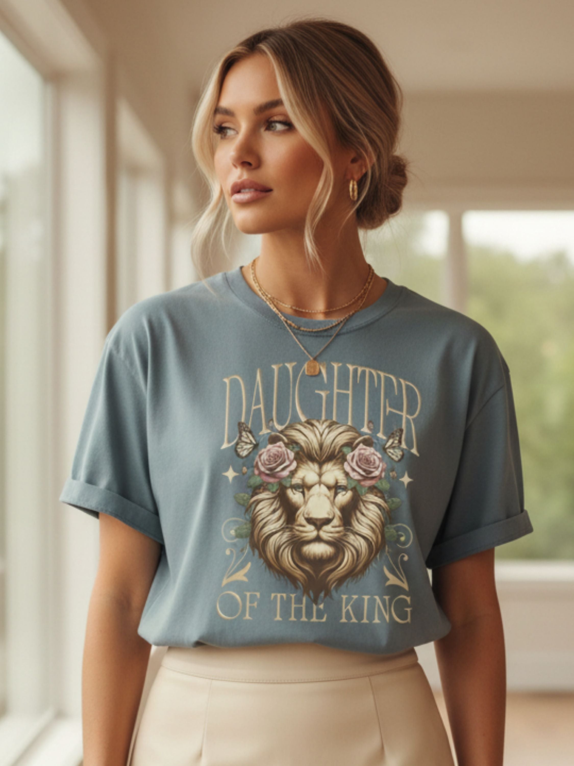 Woman wearing a blue t-shirt with a lion graphic and 'Daughter of the King' text.