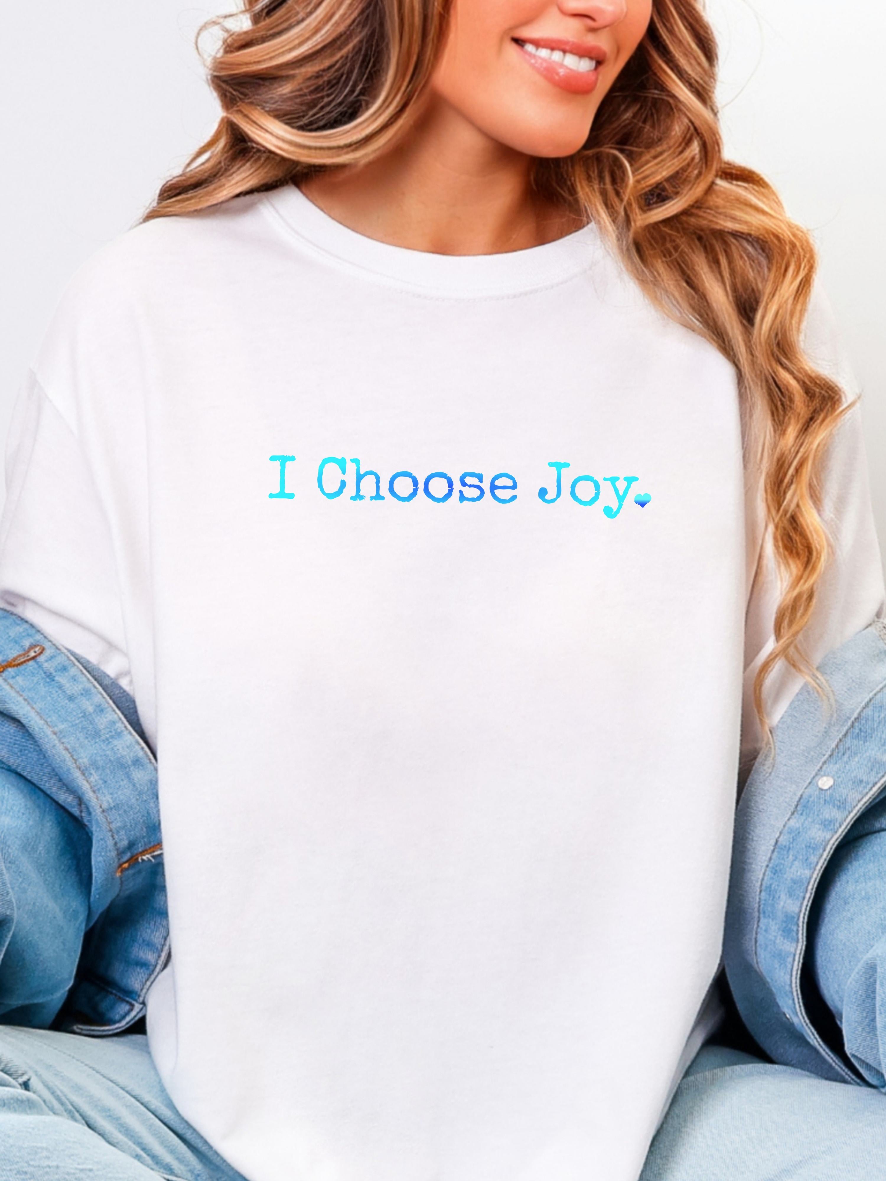 Woman wearing a white shirt with 'I Choose Joy' in shades of blue text worn under a jean jacket.
