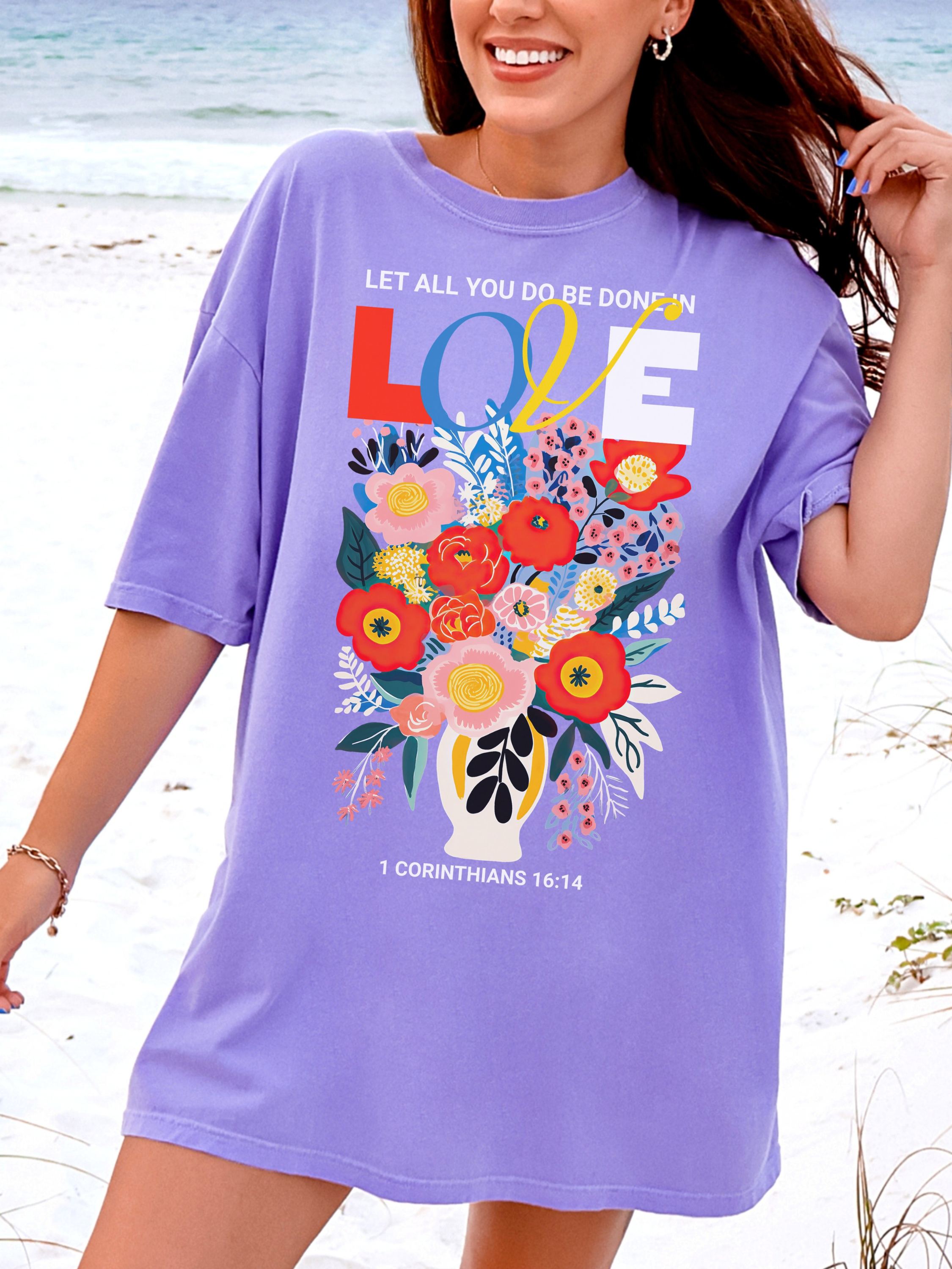 Woman wearing a purple t-shirt with floral design and text on a beach.