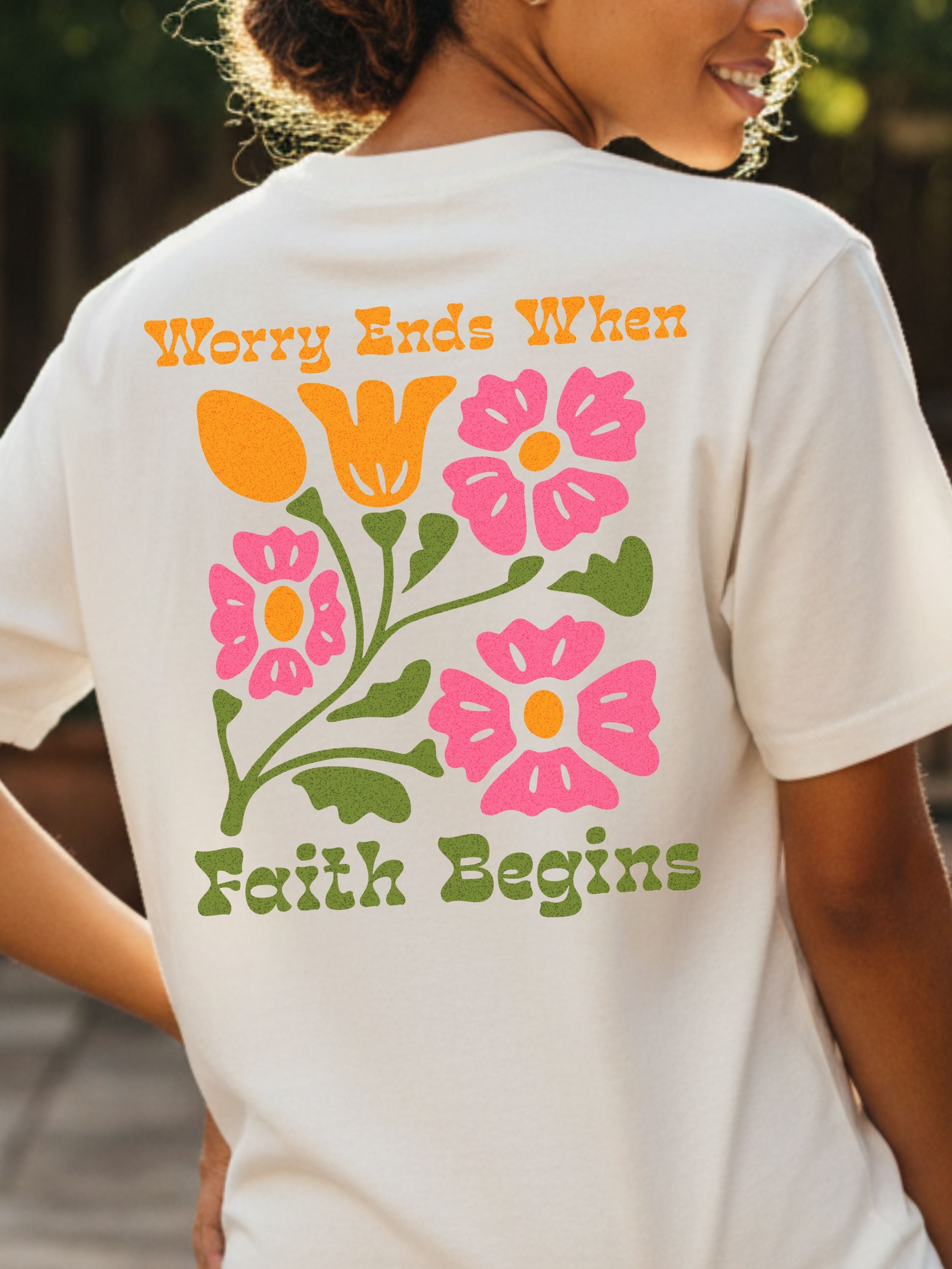 Person wearing an ivory t-shirt with floral "Worry Ends When Faith Begins" texy