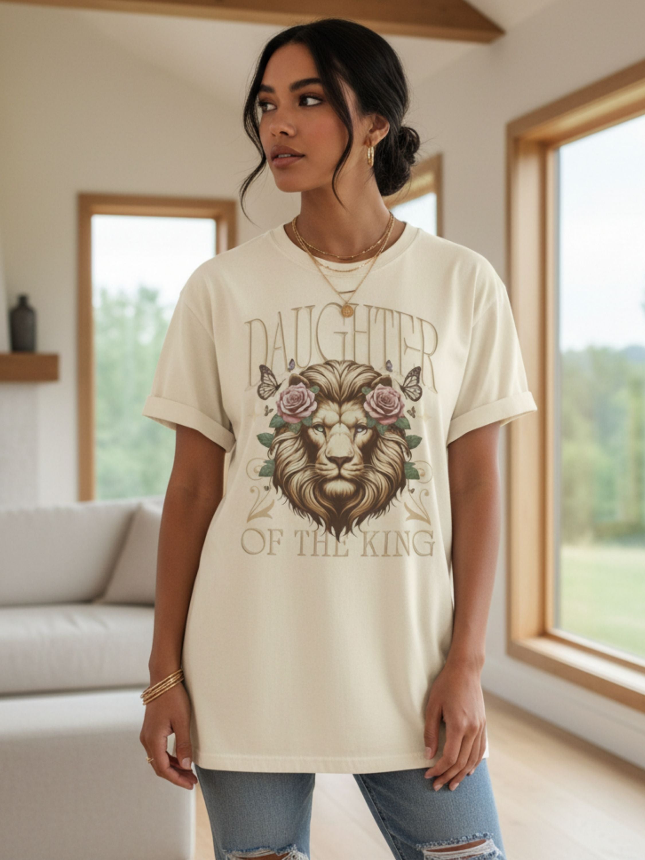 Woman wearing a cream t-shirt with a lion graphic and text in a modern living room.