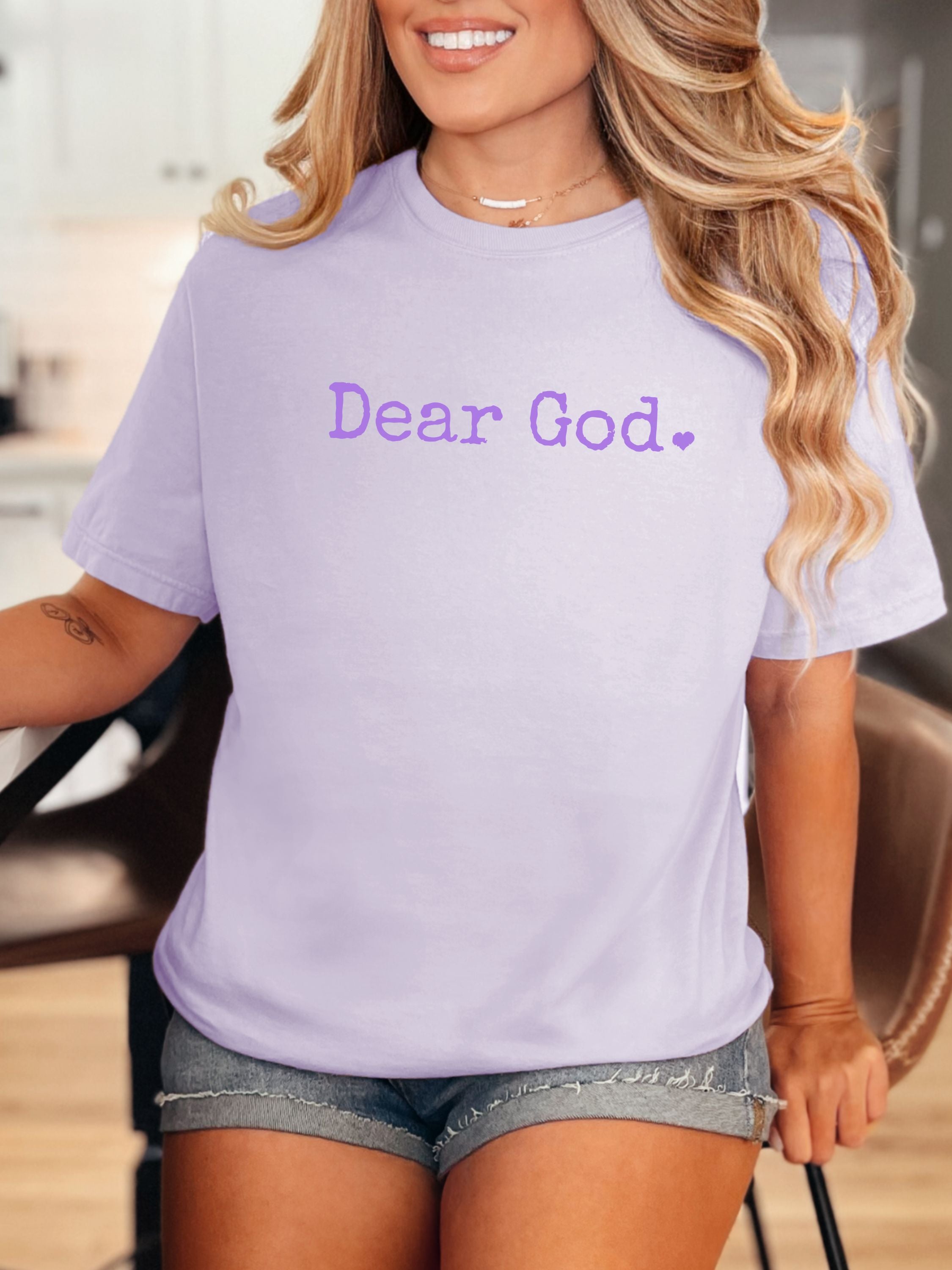 Woman wearing a light purple t-shirt with 'Dear God.' text.
