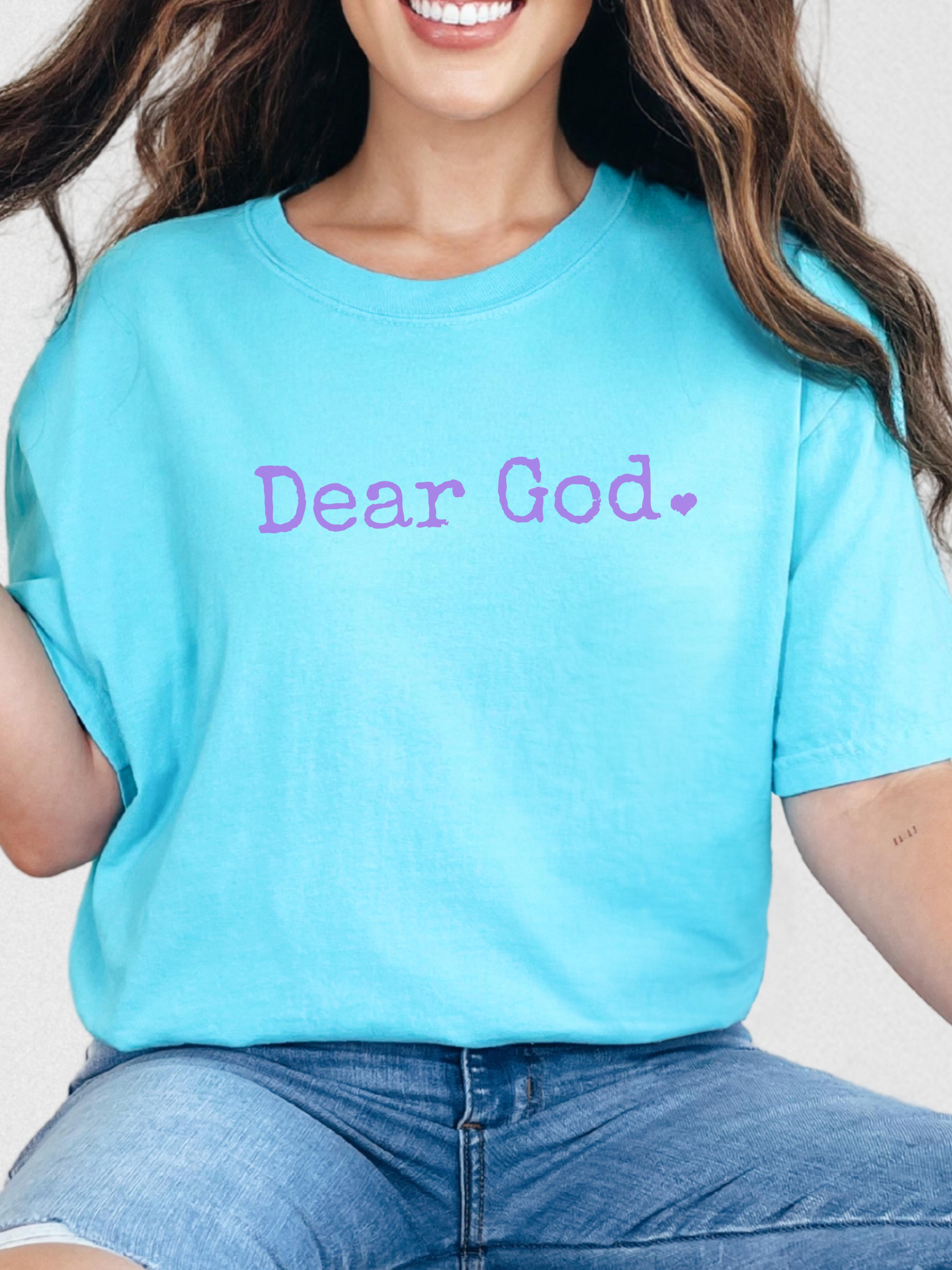Person wearing a light blue t-shirt with light purple 'Dear God' text.